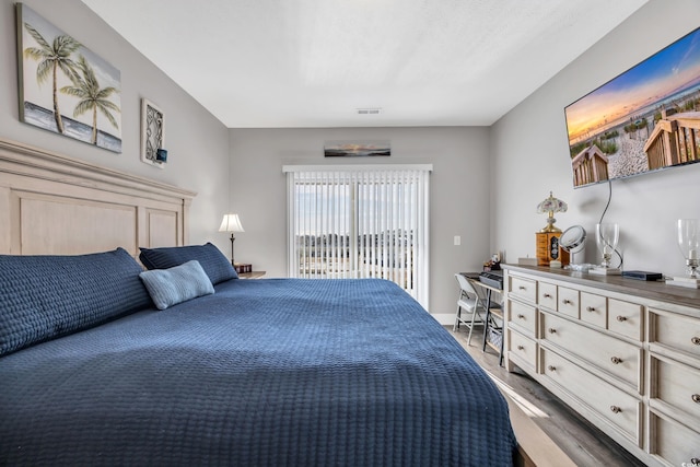 bedroom with access to outside and wood finished floors