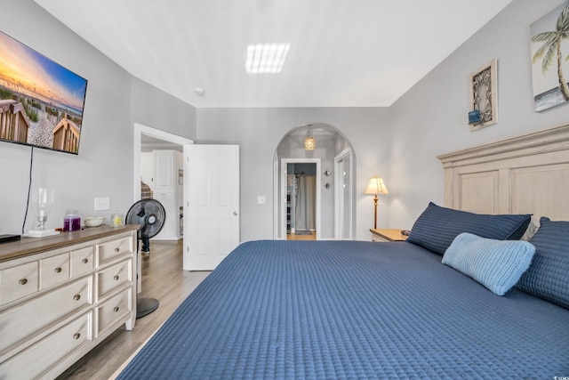 bedroom with light wood-style flooring and arched walkways