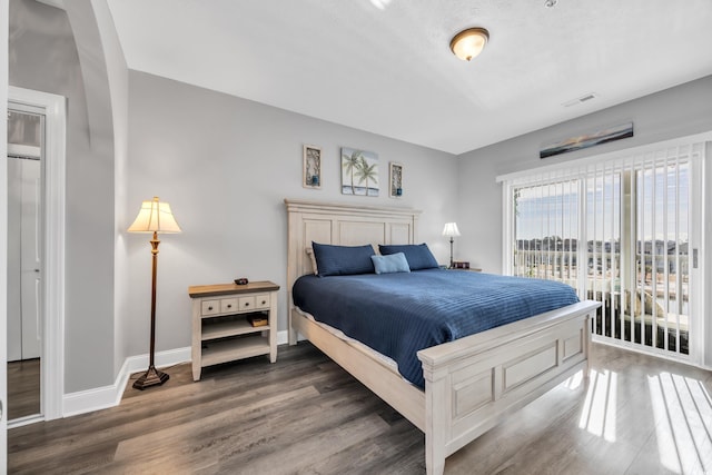 bedroom with access to outside, visible vents, baseboards, and wood finished floors