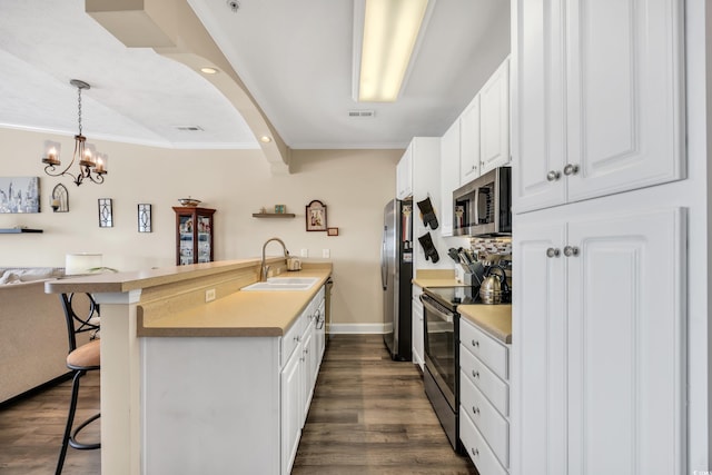 kitchen with a peninsula, a sink, white cabinets, appliances with stainless steel finishes, and a kitchen bar