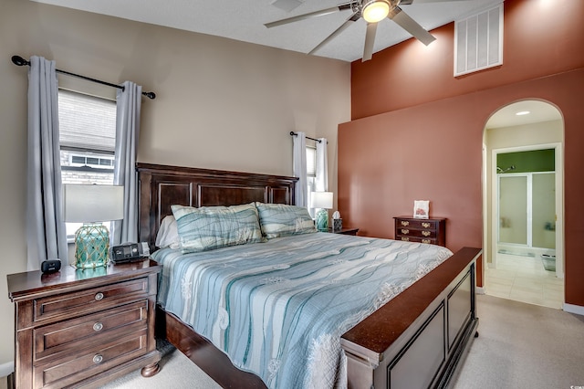 bedroom featuring visible vents, arched walkways, connected bathroom, light colored carpet, and ceiling fan