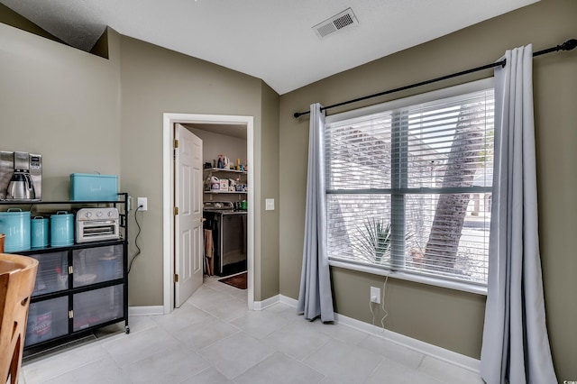 bathroom with lofted ceiling, visible vents, baseboards, and tile patterned floors