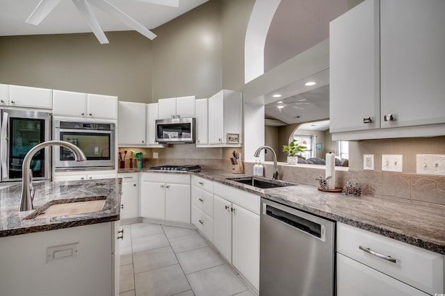 kitchen featuring appliances with stainless steel finishes, a sink, a high ceiling, and light tile patterned floors