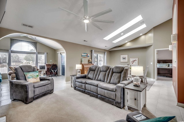 living area with high vaulted ceiling, a skylight, visible vents, and baseboards