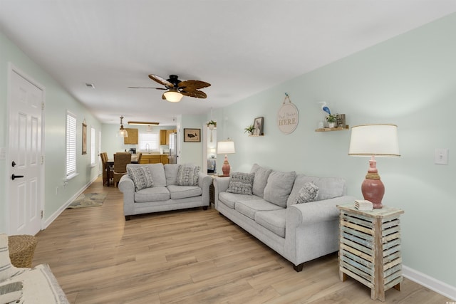 living room featuring baseboards, visible vents, light wood finished floors, and ceiling fan