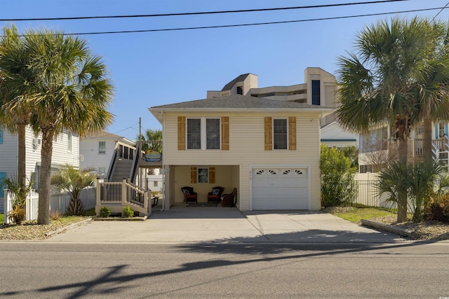 view of front of home with a garage, concrete driveway, and fence