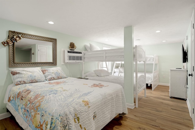 bedroom with light wood finished floors, recessed lighting, baseboards, and a wall unit AC