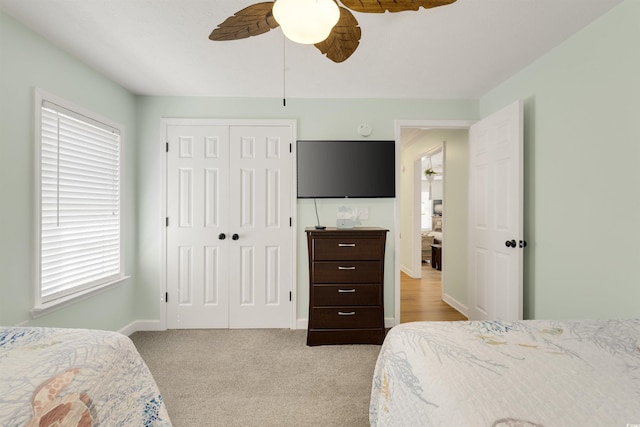 carpeted bedroom featuring a closet, ceiling fan, and baseboards