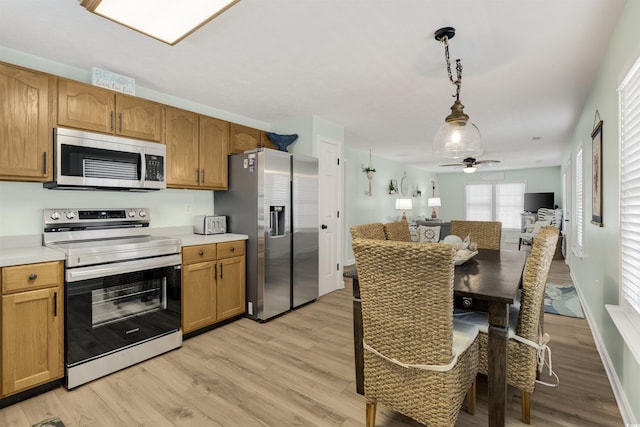 kitchen featuring stainless steel appliances, light wood finished floors, open floor plan, and light countertops