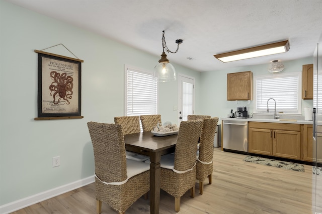 dining area with light wood-style flooring, a textured ceiling, and baseboards