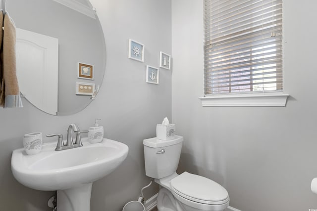 half bathroom with baseboards, a sink, and toilet