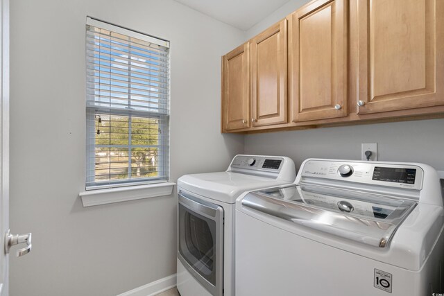 washroom with cabinet space, baseboards, and washer and dryer