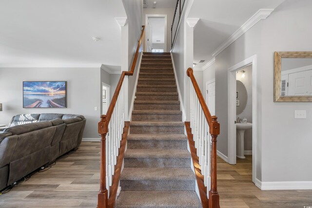 stairs with ornamental molding, wood finished floors, and baseboards