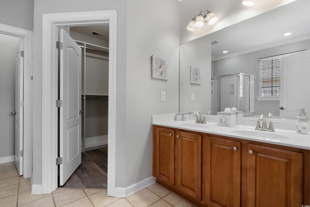 full bathroom with a sink, double vanity, a stall shower, and tile patterned flooring