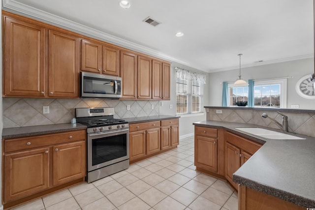 kitchen featuring stainless steel appliances, dark countertops, visible vents, brown cabinetry, and a sink