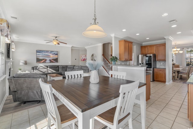 dining area featuring ceiling fan with notable chandelier, visible vents, crown molding, and light tile patterned floors