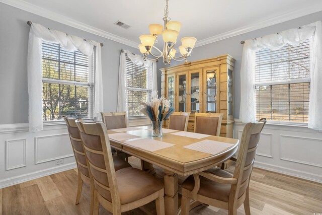 dining space featuring light wood finished floors, visible vents, and crown molding