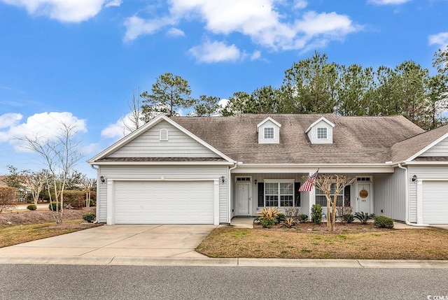 cape cod home featuring concrete driveway, a front yard, an attached garage, and roof with shingles