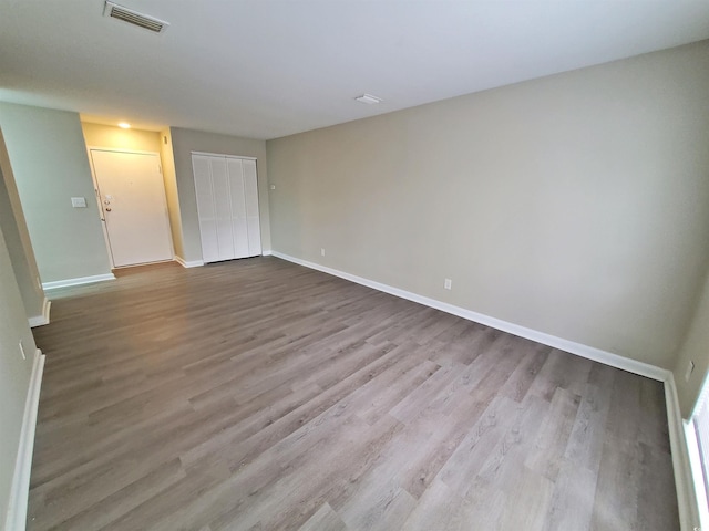 spare room featuring wood finished floors, visible vents, and baseboards