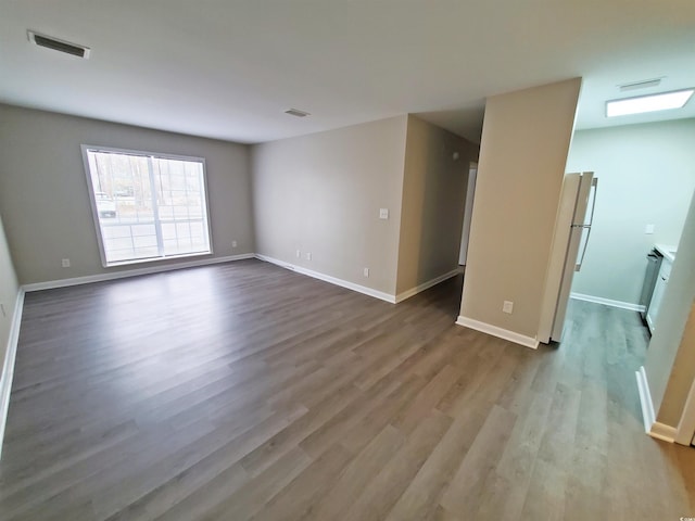 unfurnished room featuring wood finished floors, visible vents, and baseboards