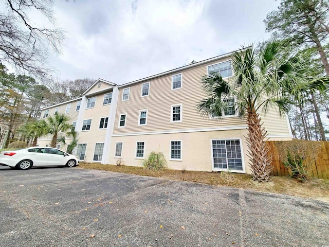 view of building exterior featuring uncovered parking and fence