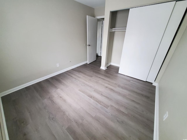 unfurnished bedroom with a closet, baseboards, and wood finished floors