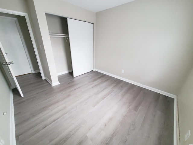 unfurnished bedroom with a closet, baseboards, and wood finished floors