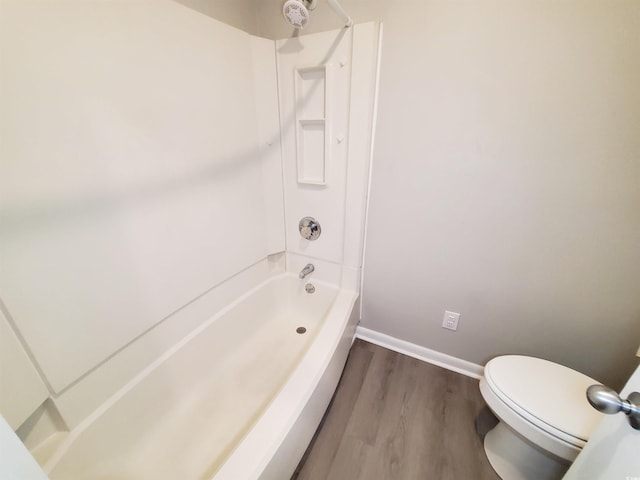 bathroom featuring toilet, bathing tub / shower combination, baseboards, and wood finished floors