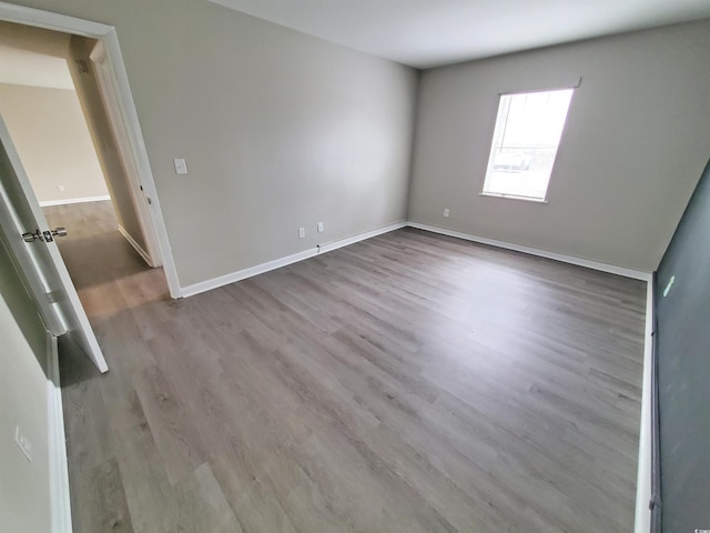 spare room with baseboards and wood finished floors