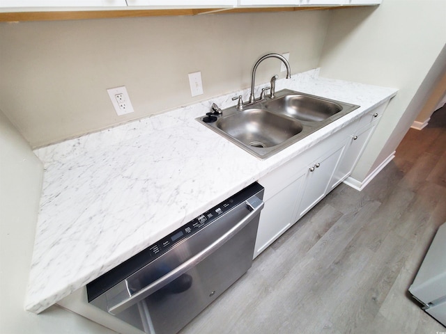 kitchen with baseboards, white cabinets, wood finished floors, stainless steel dishwasher, and a sink