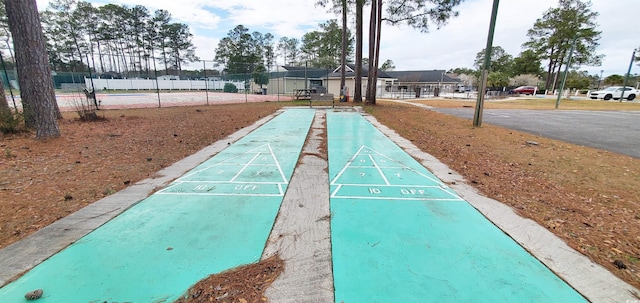 view of home's community with fence and shuffleboard