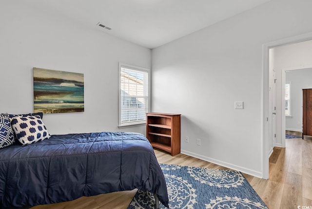 bedroom with light wood-type flooring, baseboards, and visible vents