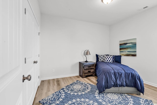 bedroom featuring baseboards, visible vents, and light wood finished floors