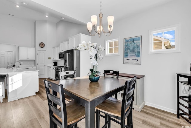 dining room featuring a healthy amount of sunlight, light wood finished floors, baseboards, and a chandelier