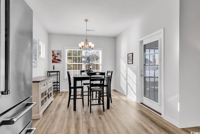 dining space featuring light wood finished floors, plenty of natural light, visible vents, and an inviting chandelier