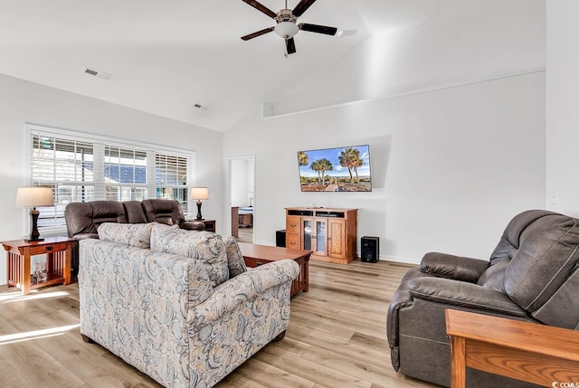 living area featuring high vaulted ceiling, light wood-type flooring, visible vents, and a ceiling fan