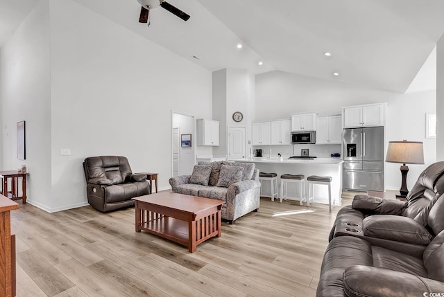 living area featuring high vaulted ceiling, recessed lighting, a ceiling fan, baseboards, and light wood finished floors