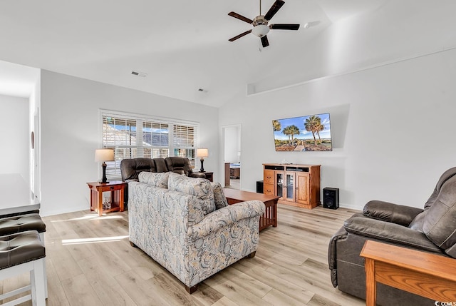 living room featuring light wood-style floors, visible vents, ceiling fan, and high vaulted ceiling