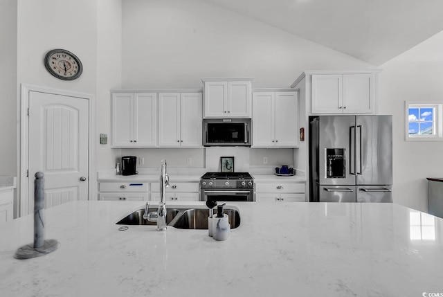 kitchen featuring a sink, light stone counters, white cabinets, and premium appliances