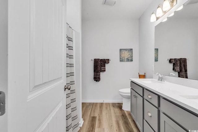 bathroom with toilet, wood finished floors, visible vents, a sink, and double vanity