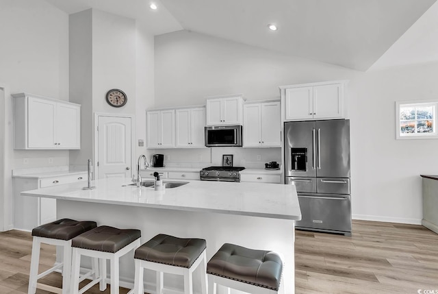 kitchen with white cabinets, a kitchen bar, stainless steel appliances, and a sink