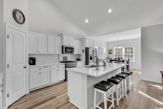 kitchen featuring a breakfast bar area, appliances with stainless steel finishes, a kitchen island with sink, a sink, and white cabinetry