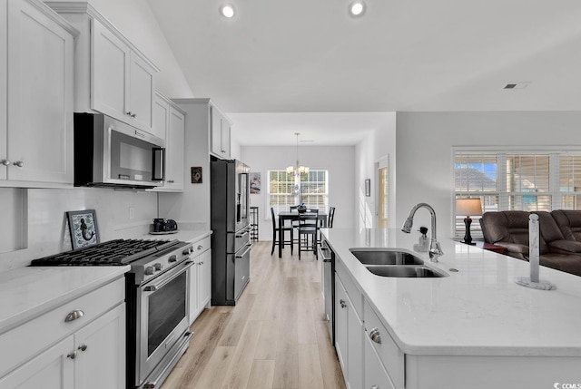 kitchen featuring light wood finished floors, visible vents, appliances with stainless steel finishes, a kitchen island with sink, and a sink