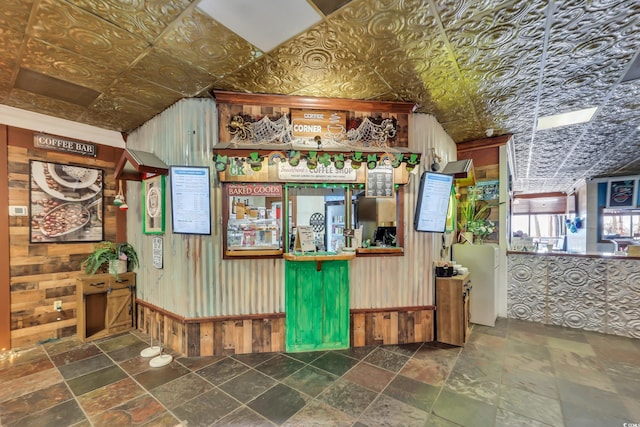 interior space with wood walls, an ornate ceiling, and stone tile flooring