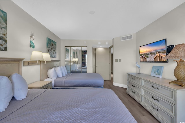 bedroom with visible vents, baseboards, and wood finished floors