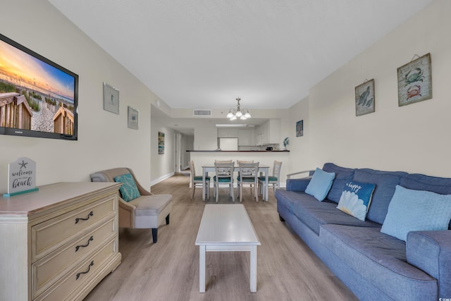 living room featuring visible vents, baseboards, a notable chandelier, and light wood-style flooring