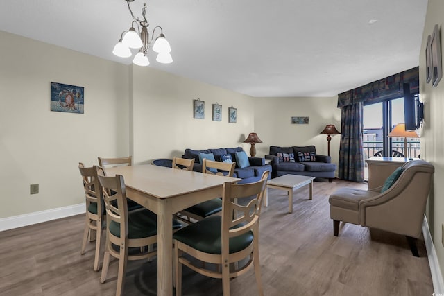 dining space featuring baseboards, an inviting chandelier, and wood finished floors