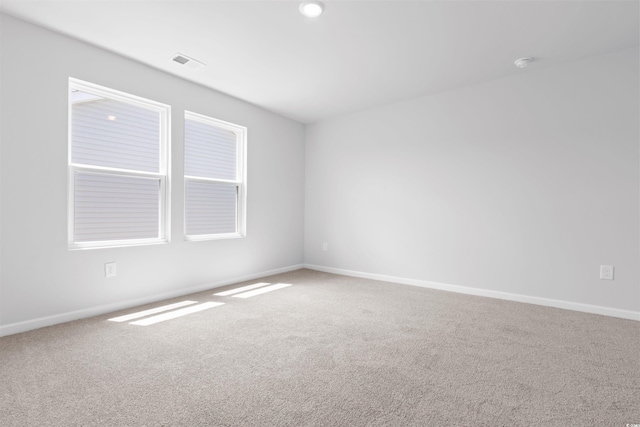 unfurnished room featuring carpet floors, visible vents, and baseboards