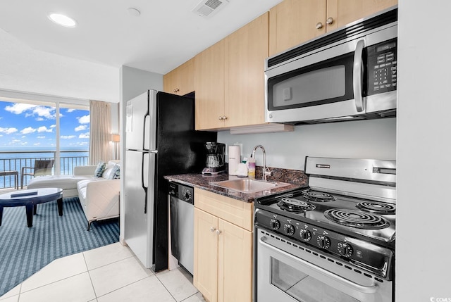 kitchen with visible vents, stainless steel appliances, light brown cabinetry, a sink, and light tile patterned flooring