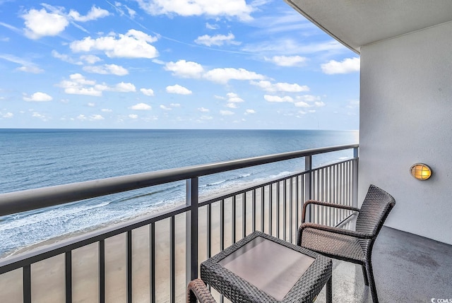 balcony with a water view and a view of the beach